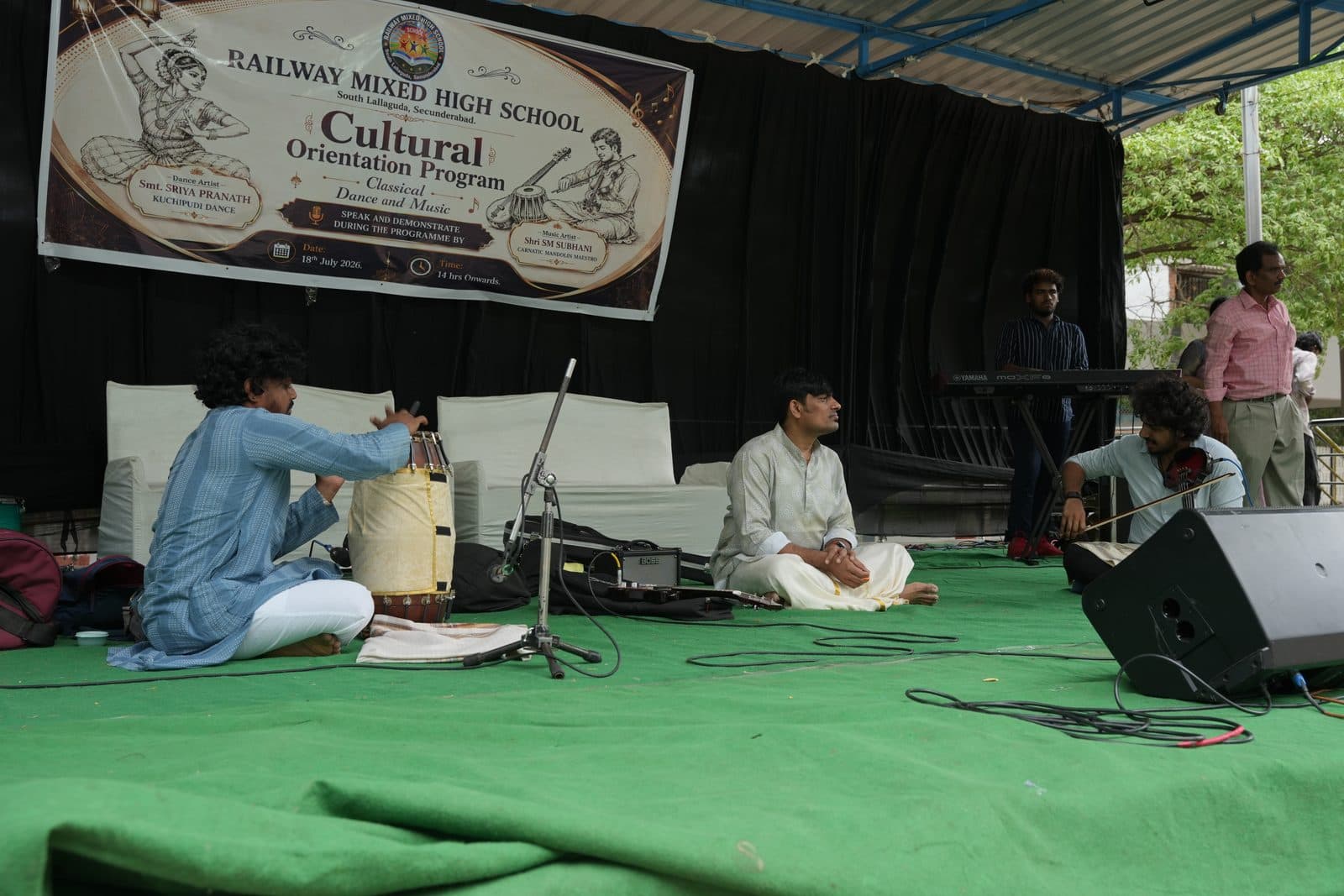 Musicians performing seated on a stage during the school's cultural orientation programme