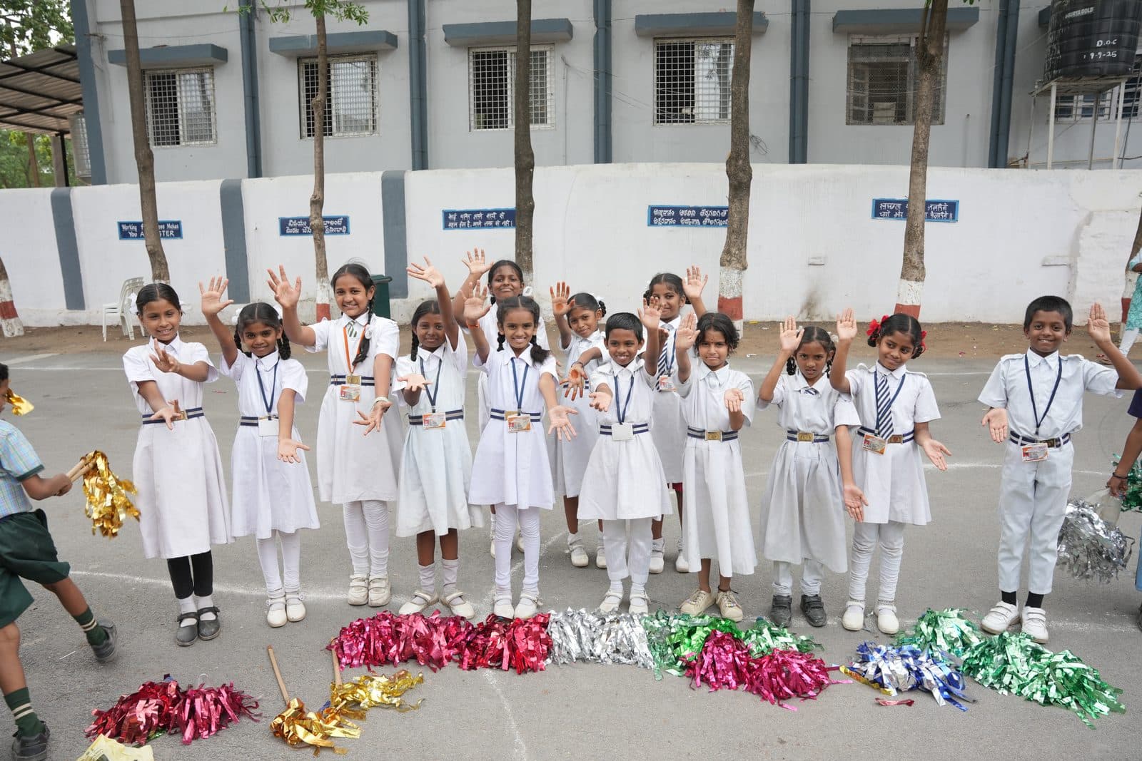 Students in white uniform smiling and waving at the camera