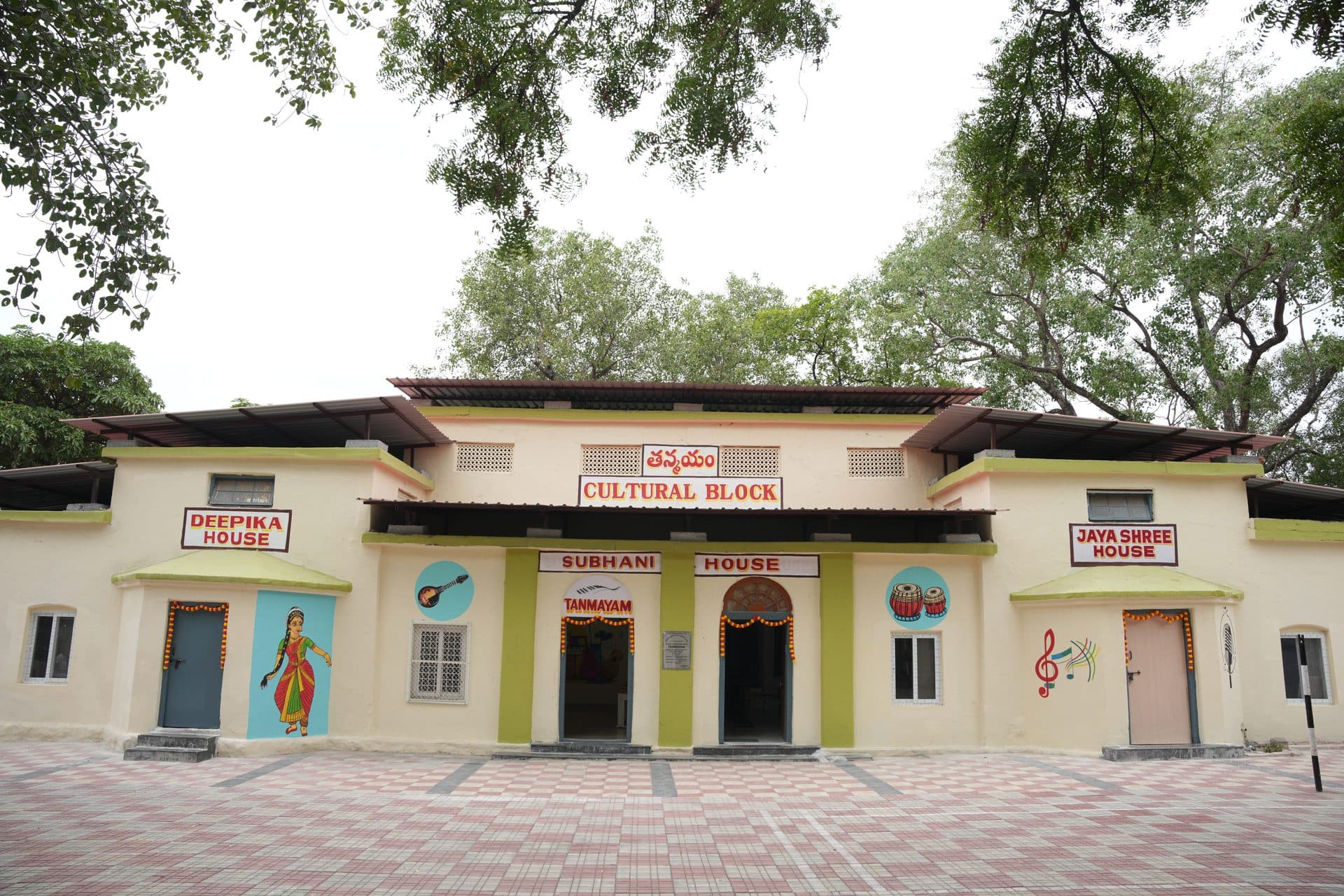 The Tanmayam cultural block, painted in cream and green, with signage for the Deepika, Subhani and Jayashree houses